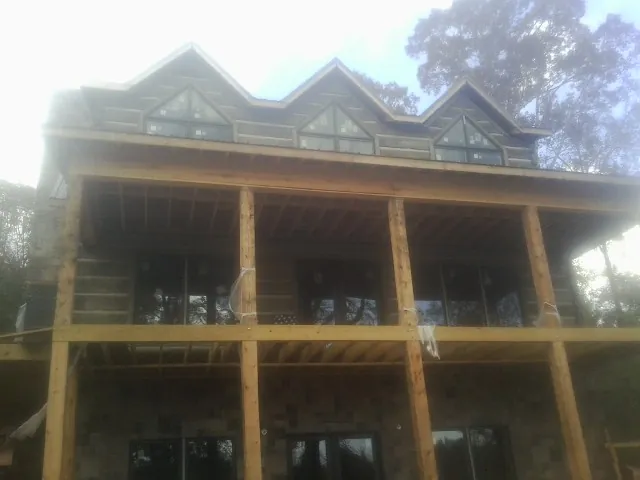 Dormers and porch framing on a large log home under construction — Roof Coating work by our crew in Occoquan
