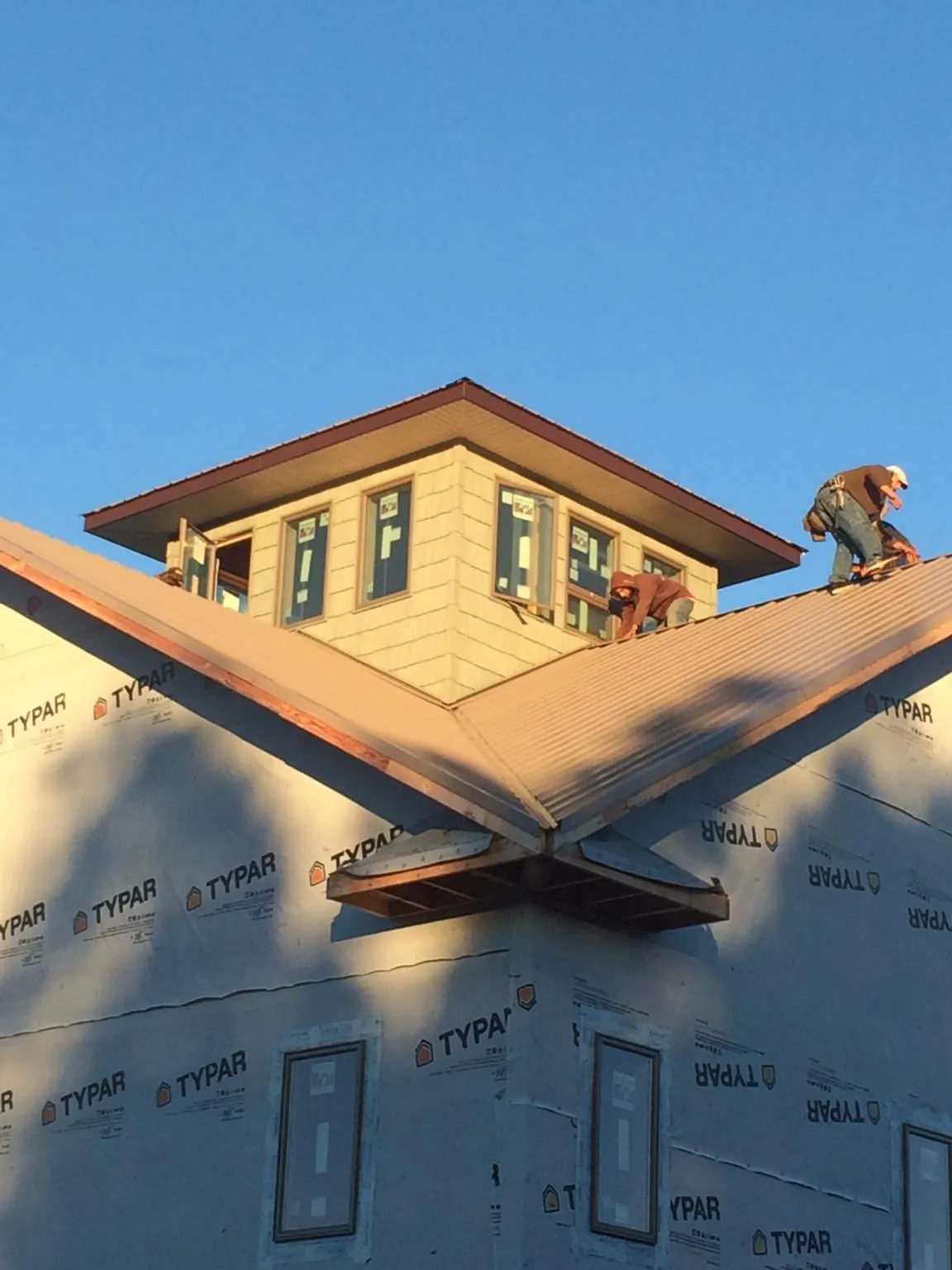 Roofers working around a rooftop cupola on a new metal roof at sunset — Roof Waterproofing in Occoquan by Roofing Brothers